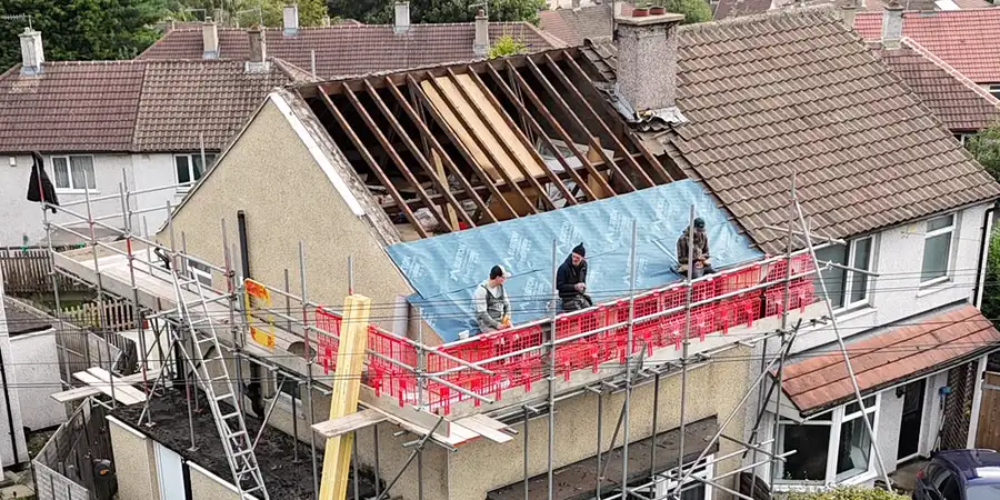 The team working on the scaffold of a stripped roof, with a breathable membrane over the rafters