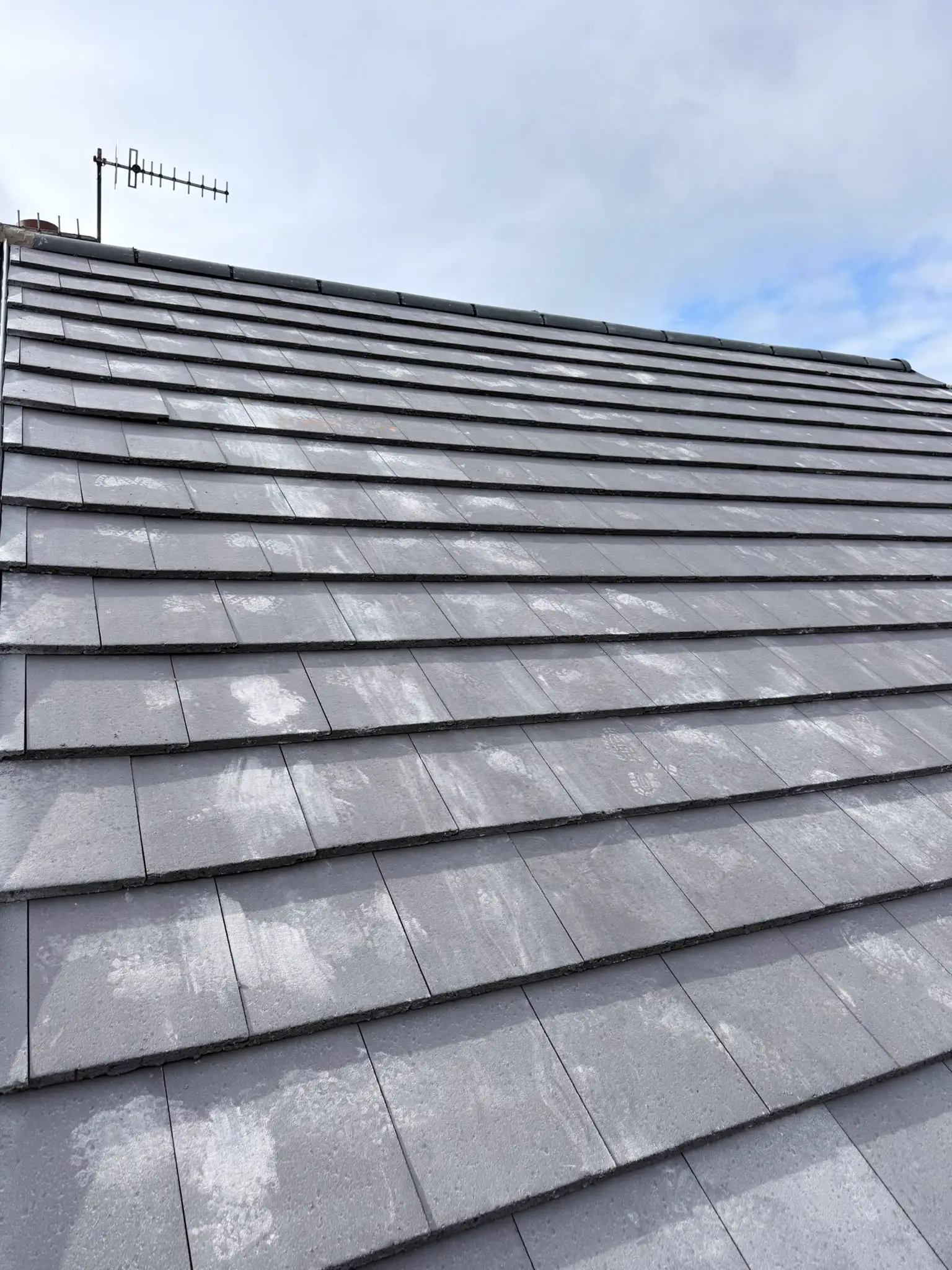 A newly laid grey tiled roof under a blue sky