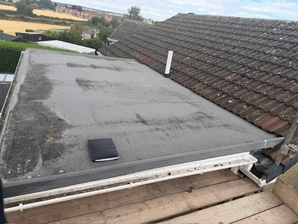 Before: a worn, patchy flat roof covering beside a tiled roof