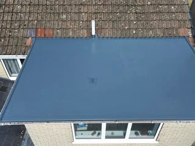 After: the same flat roof re-covered in a smooth new grey membrane, seen from above