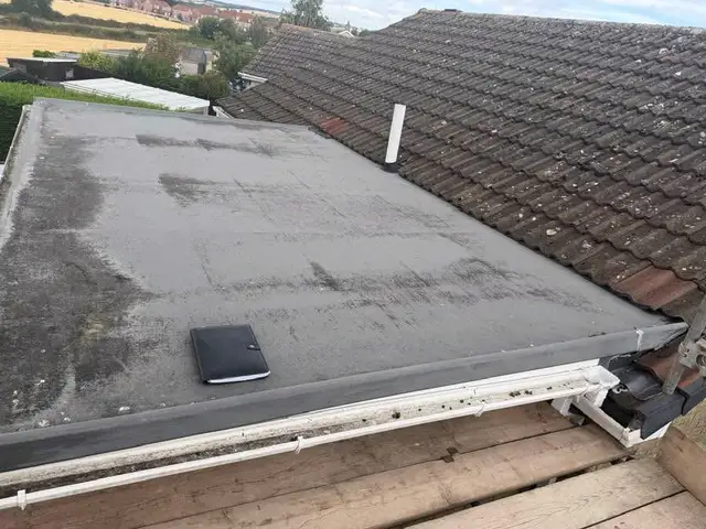 Before: a worn, patchy flat roof covering beside a tiled roof