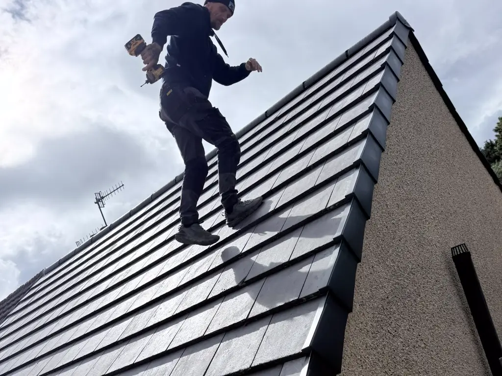 One of the Fox Roofing team on a newly tiled roof, drill in hand